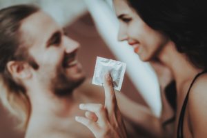 Mulher segurando e mostrando o preservativo ao homem