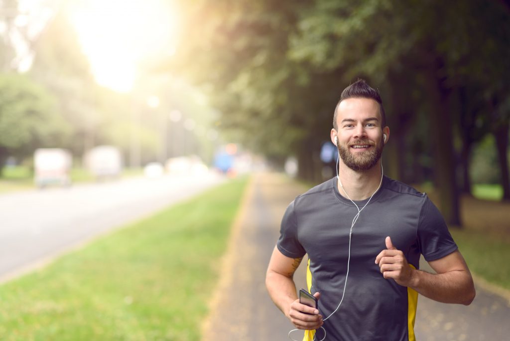 Homem feliz e sorrindo correndo na rua com blusa de esporte