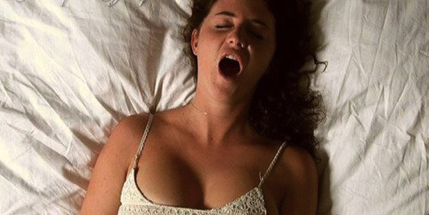 mulher deitada na cama com uma expressão de prazer