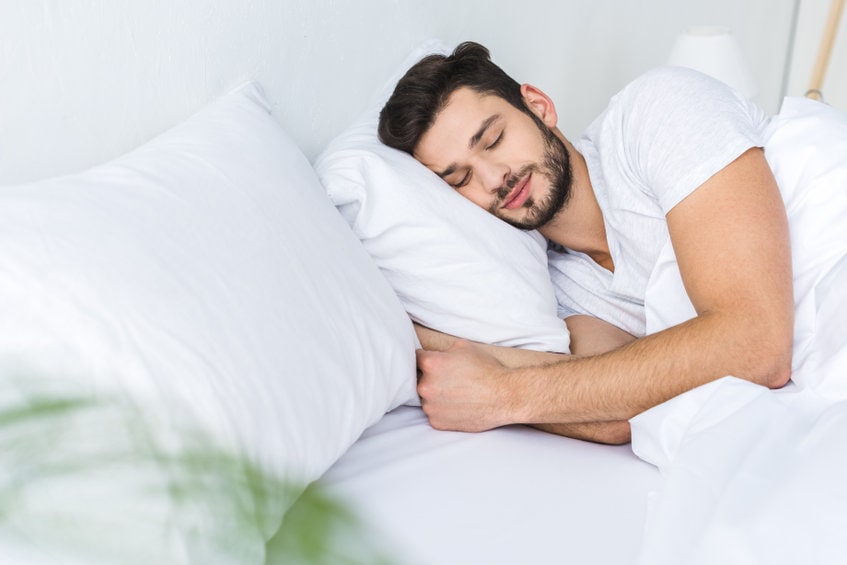 Homem dormindo na cama representando os benefícios da masturbação que é a melhoria do sono 