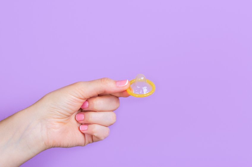 mão segurando preservativo para proteção do sexo na gravidez