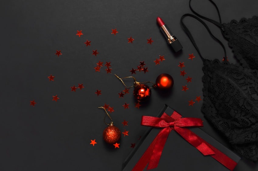 Fundo preto com itens vermelhos de natal, sutiã preto e batom vermelho