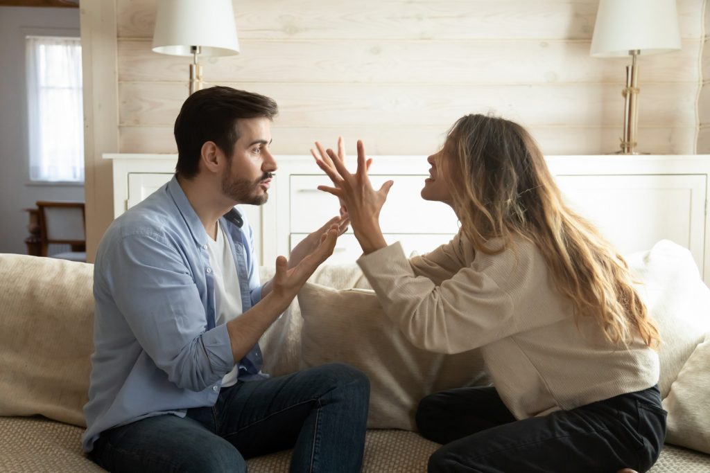 Homem e mulher sentados, brigando no sofá devido ao relacionamento tóxico