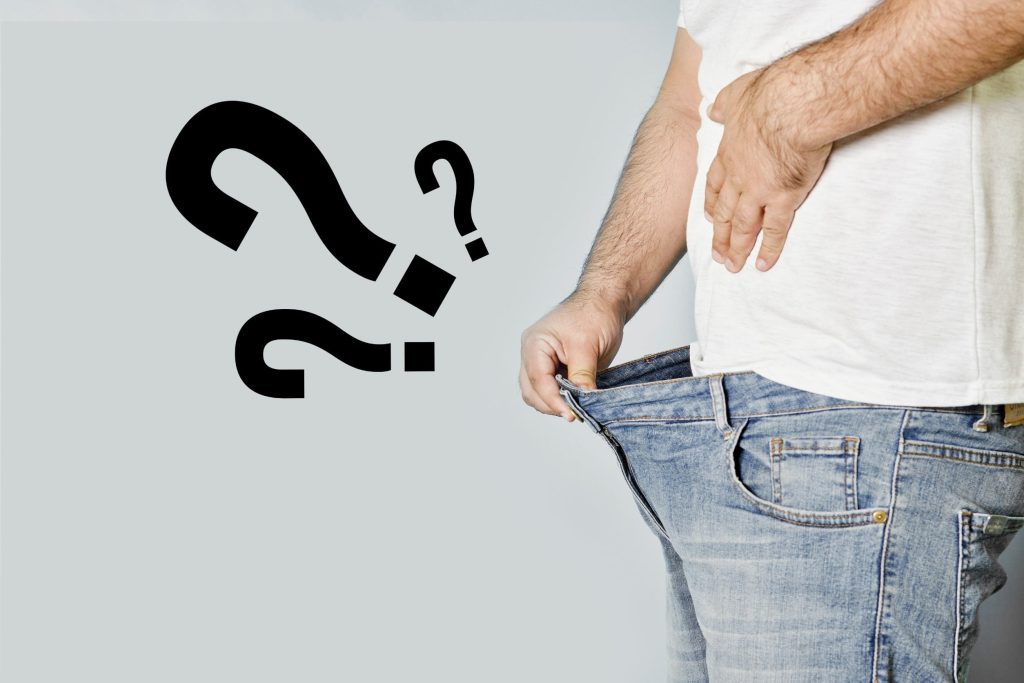 Homem abrindo a calça com pontos de interrogação do lado remetendo a disfunção erétil, principal motivo do uso de viagra natural 