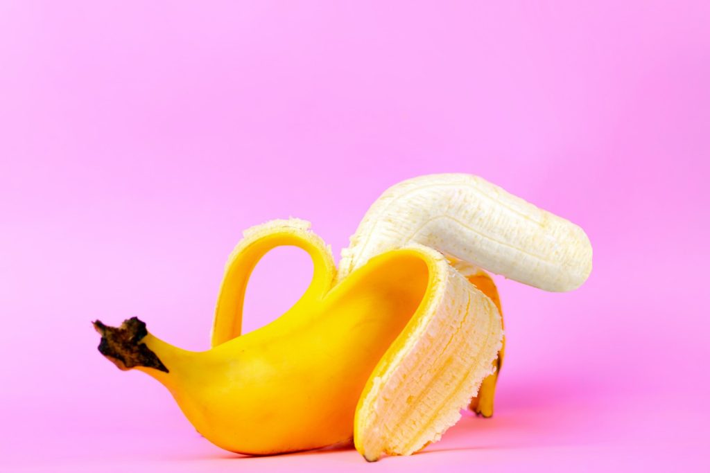 Foto de uma banana descascada até a metade, onde a parte descascada esta curvada, representado a doença de peyronie
