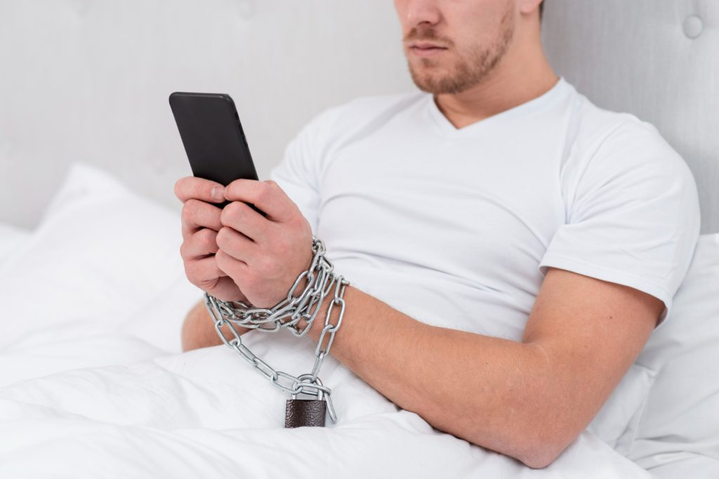 homem com vicio em pornografia segurando o celular