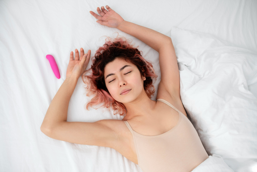 mulher deitada na cama ao lado de um vibrador golfinho rosa
