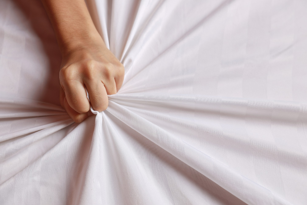 mão puxando o tecido do lençol para ilustrar o conteúdo sobre como gozar rápido da DSS